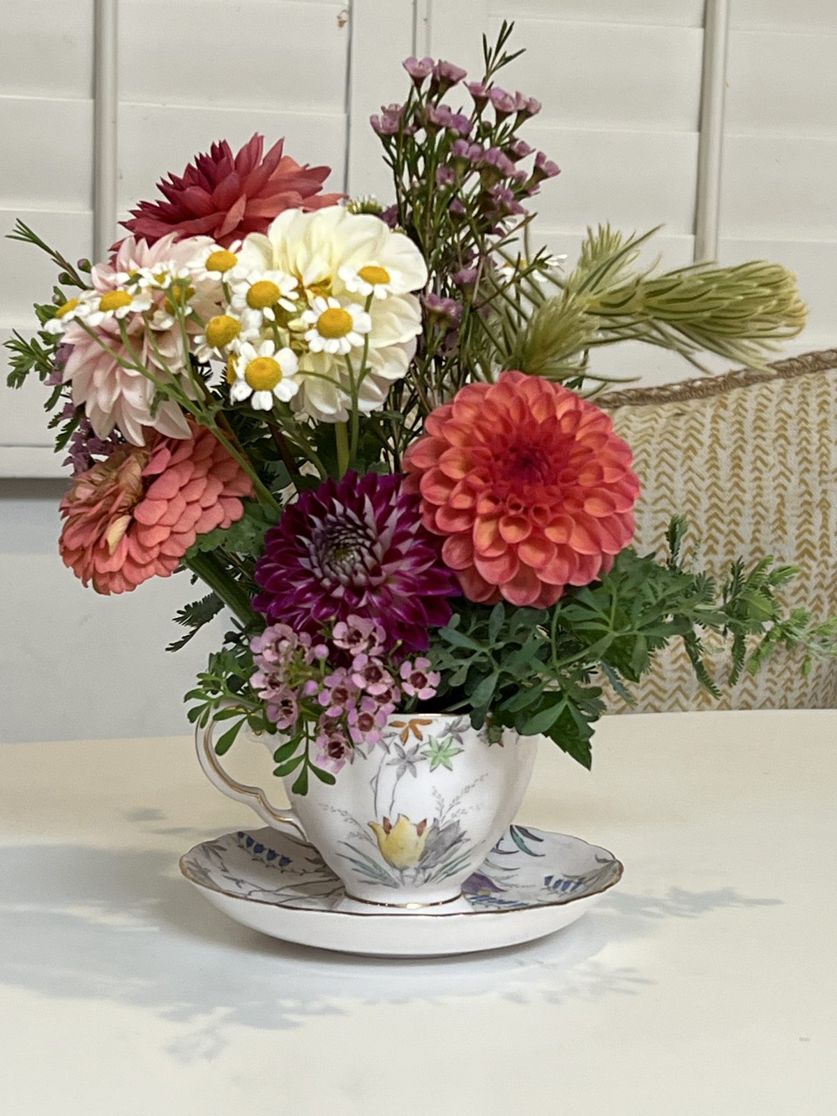 A small posy of dahlias, banksia and strawflower hung on a white door