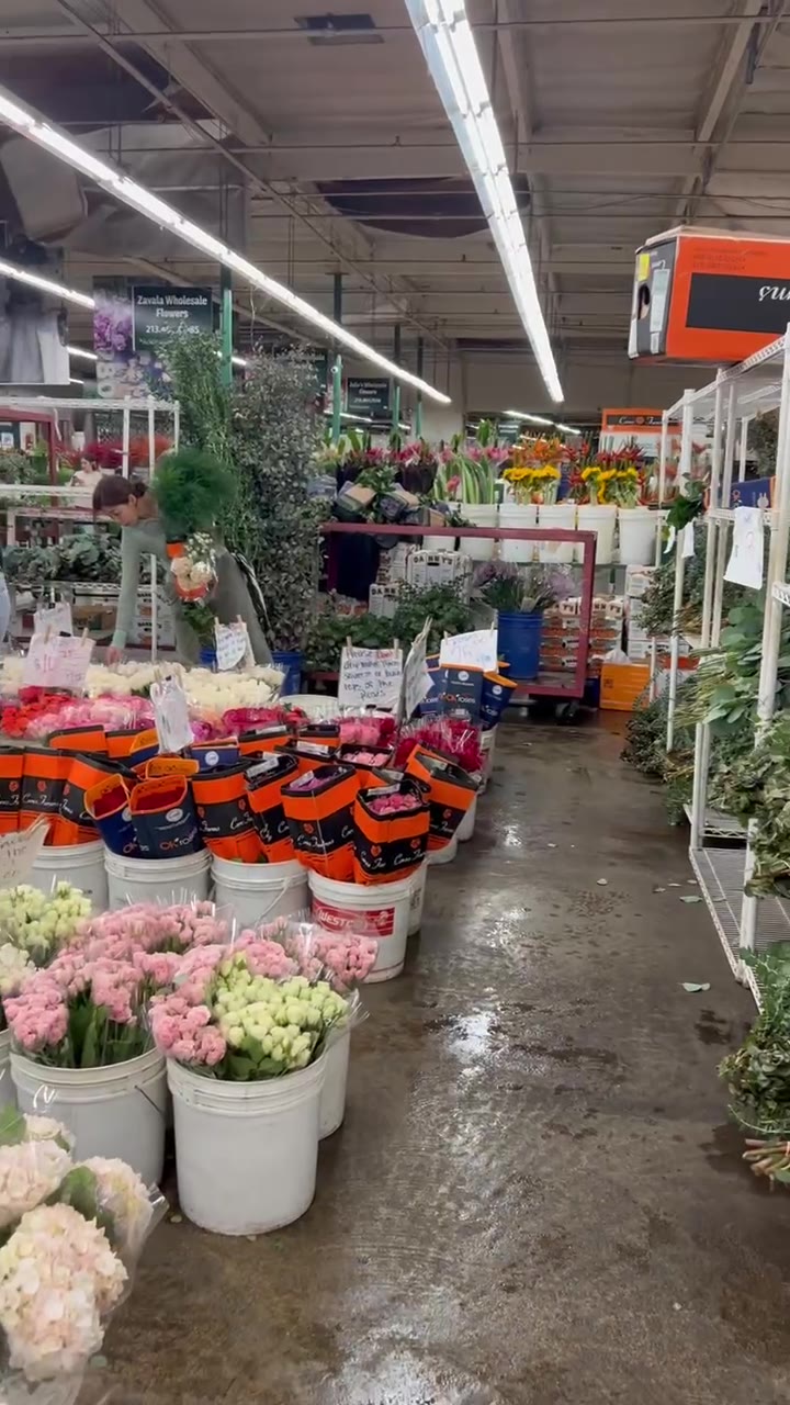 An aisle of the LA flower market lined with buckets of pink and white stems