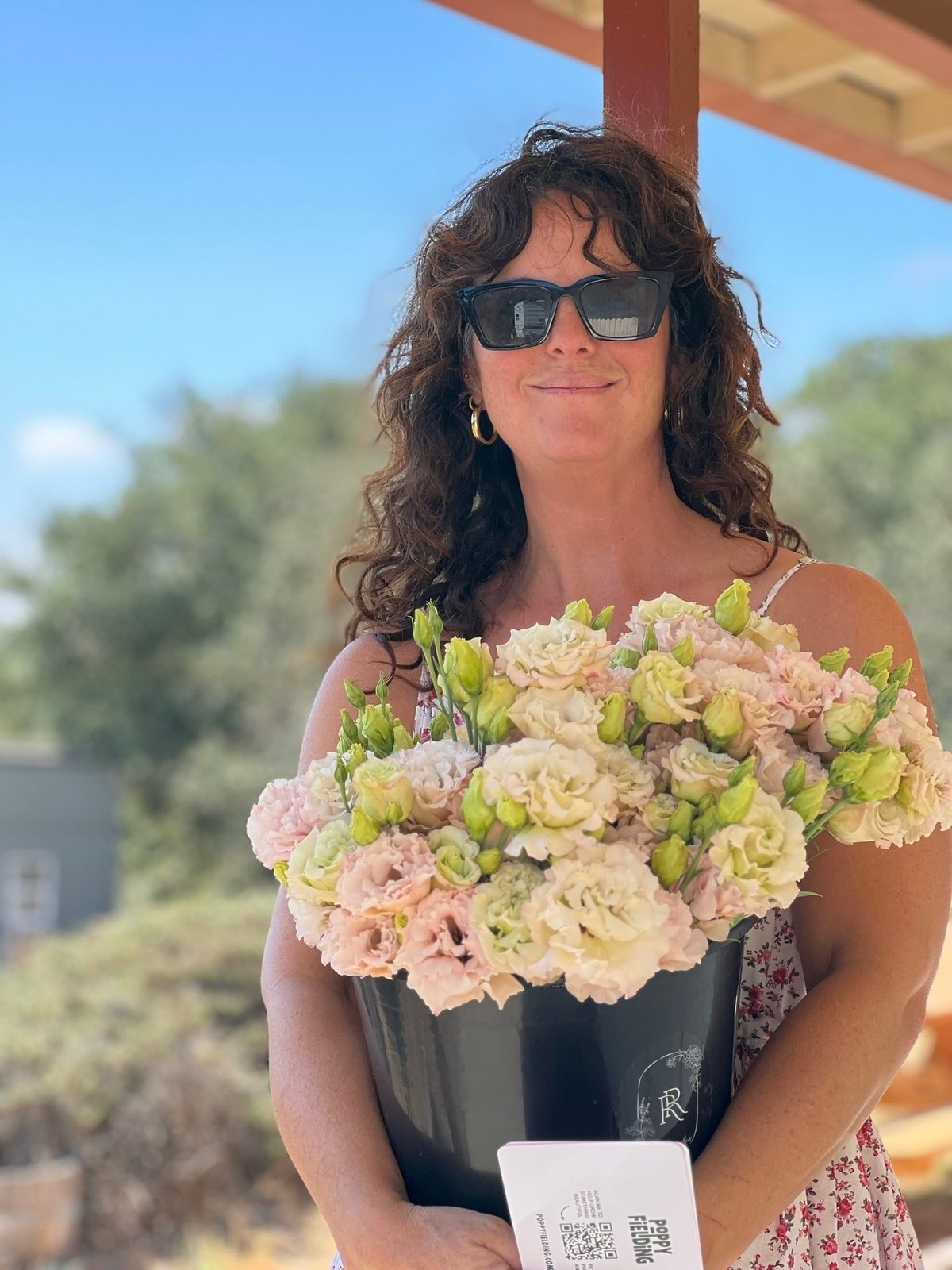 Carrie holding a bucket of blush lisianthus and a Poppy Fielding card